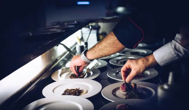 Chef plating food on a commercial kitchen line