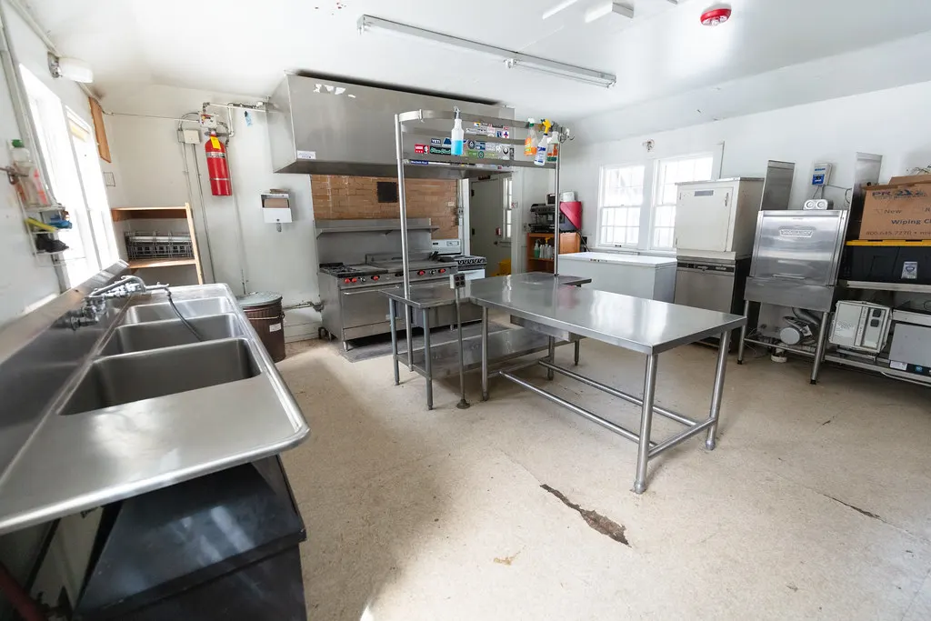 Commercial kitchen with three-compartment sink and prep tables